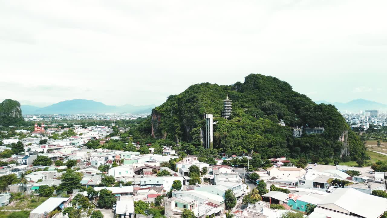 Scenic aerial approach to Marble Mountains in Da Nang, Vietnam with lush green surroundings, drone establishing