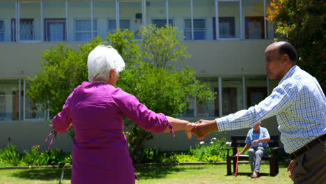 side view of active mixed-race senior couple dancing together in the garden of nursing home 4k