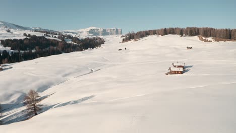 dron dolly adelante disparó sobre nieve espesa y cabañas de montaña seiser alm dolomitas italianas