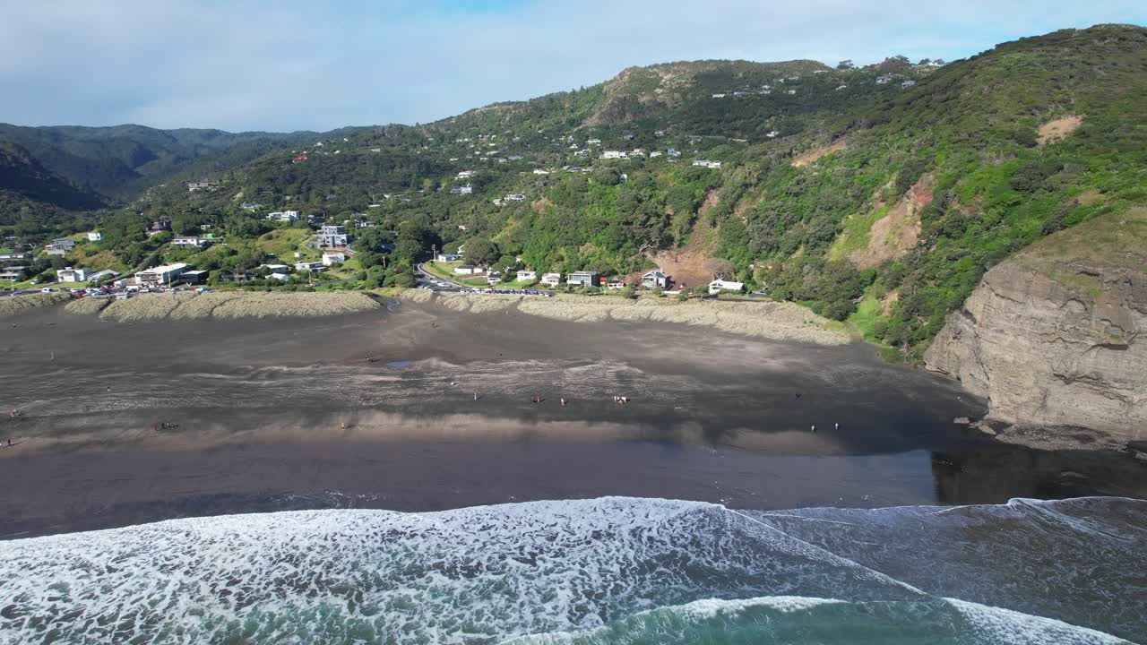 Turistas en la playa de arena negra de Piha en un día soleado de verano en West Auckland, Nueva Zelanda