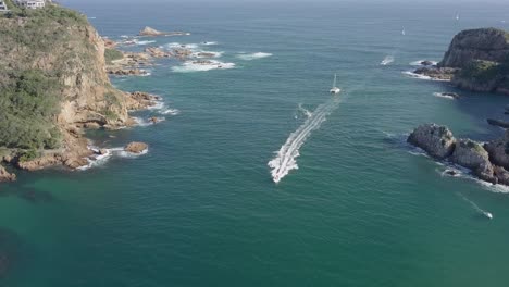 Boats-returning-to-Knysna-South-Africa-pass-through-the-Heads,-aerial