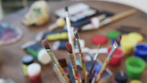 close up of paints and brushes on table in studio, slow motion