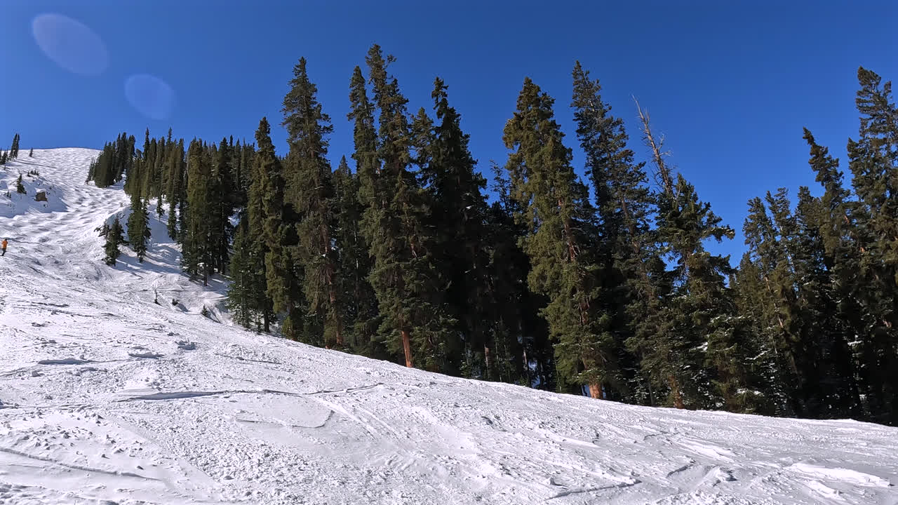Una fluida panoramica dalla base di una pista da sci rivela l'intera distesa del pendio innevato sovrastante