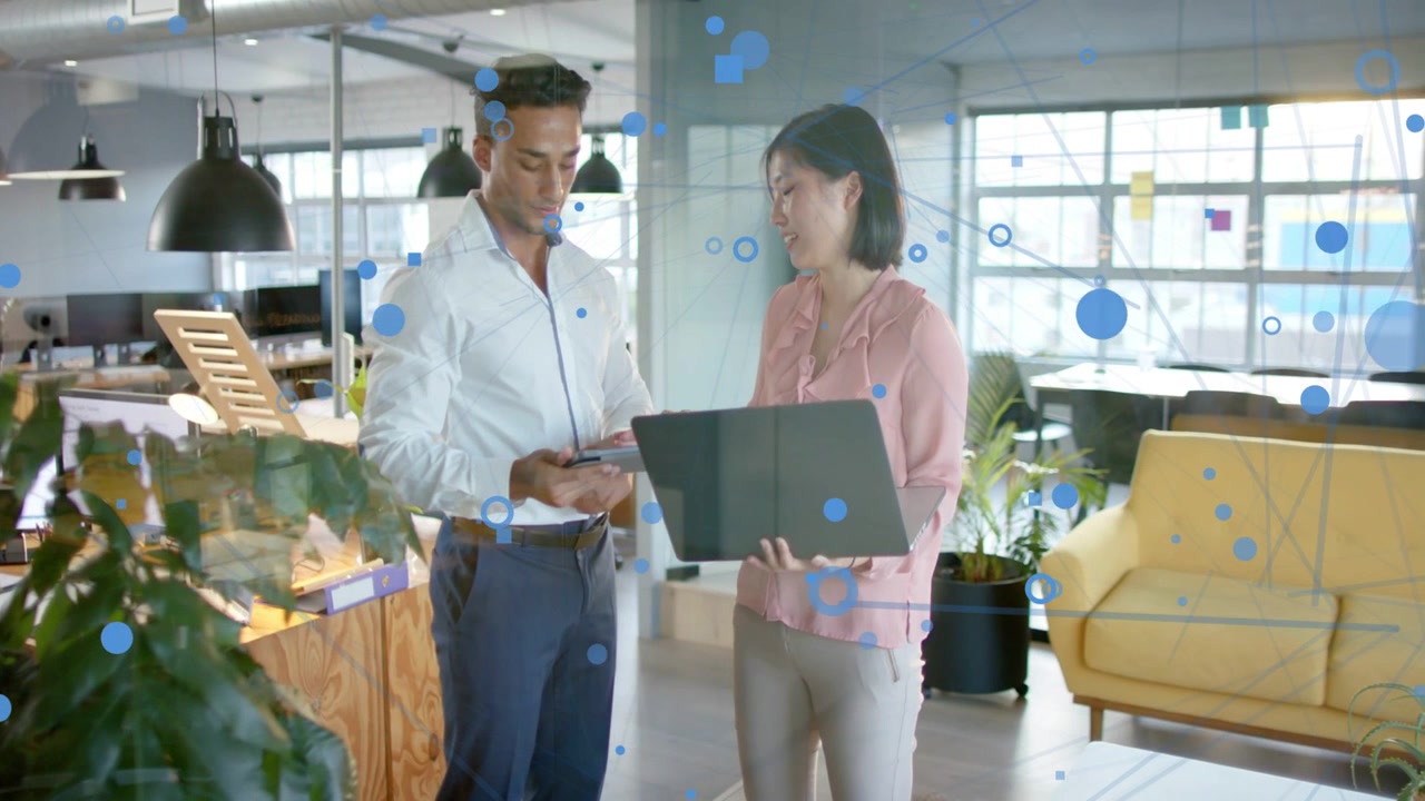 Mujer sosteniendo un portátil y señalando, hombre cambiando a una tableta y pulsando, con una superposición azul mostrando datos empresariales.