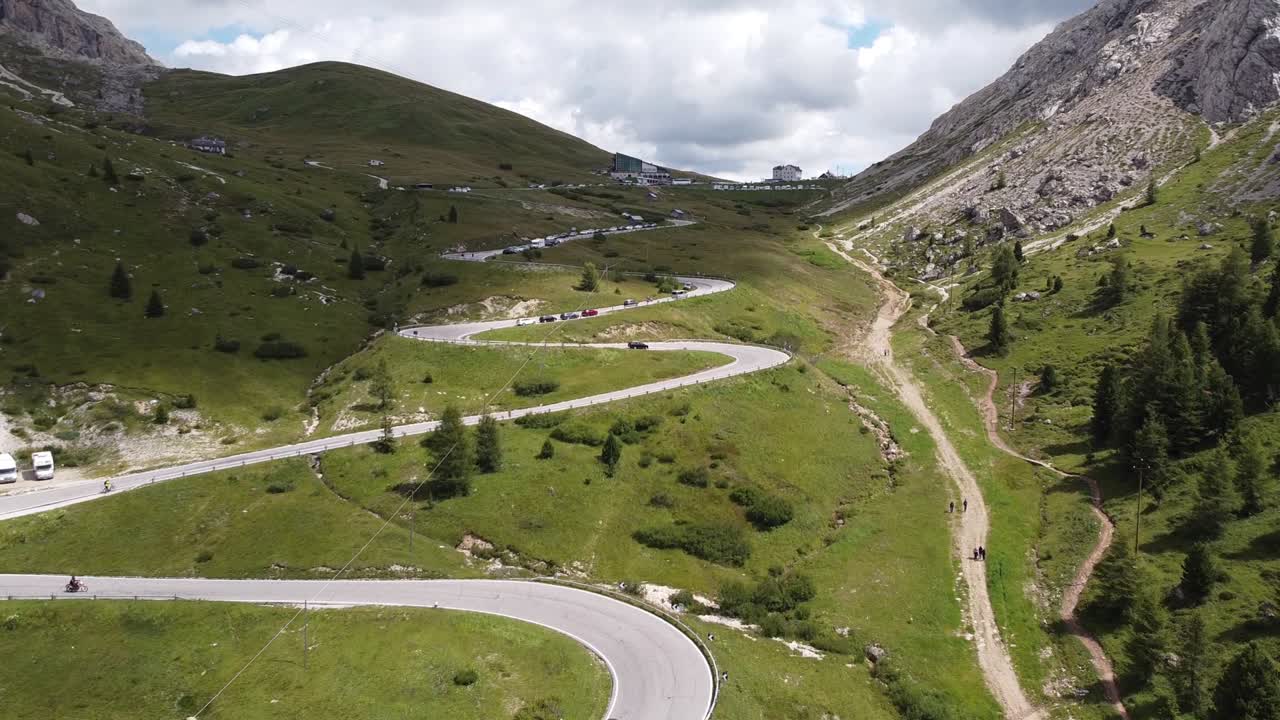 paso de montaña pordoi en trentino, tirol del sur, dolomitas, italia - vista aérea de drones de automóviles conduciendo las curvas cerradas hasta la cima de la montaña