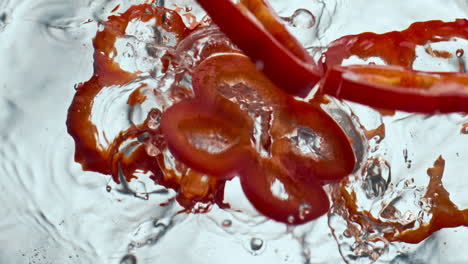 sliced red pepper falling water in super slow motion. closeup vitamin vegetable