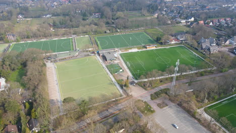 wide jib up of green soccer fields at the edge of small town