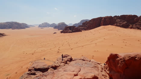 pan a través de una persona caminando hacia el borde del acantilado por encima de una vista panorámica del desierto