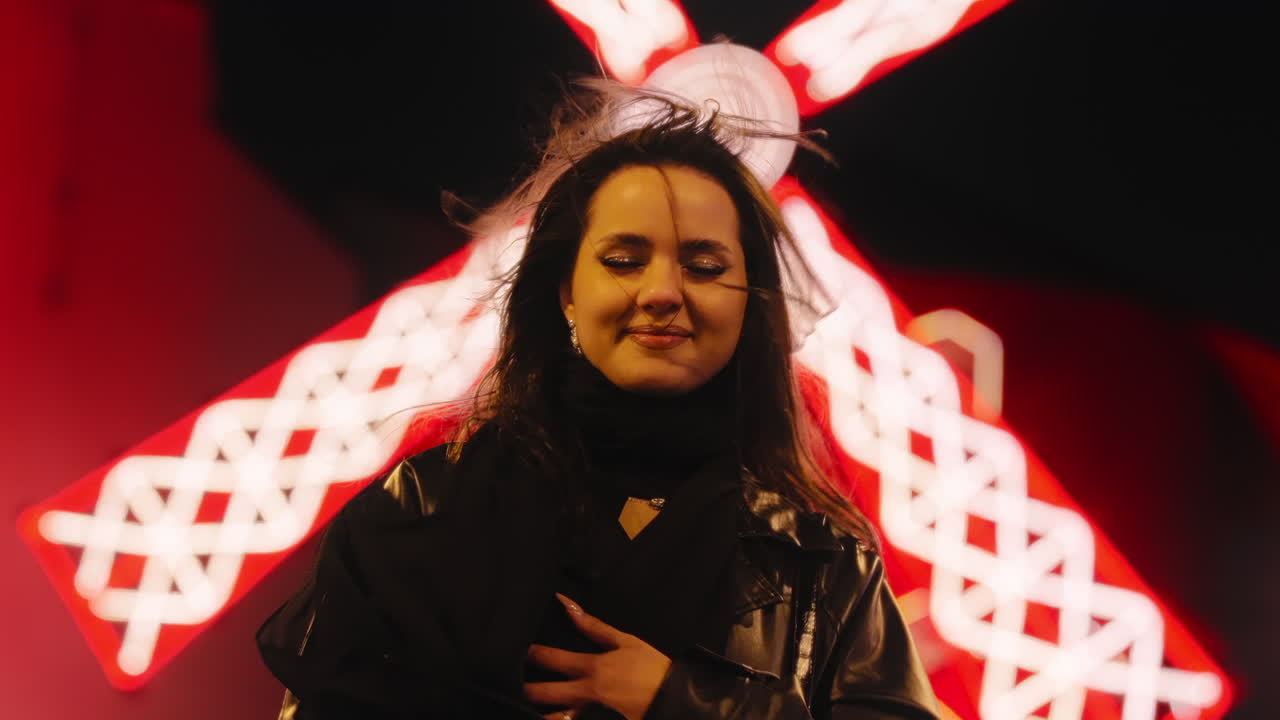 mujer modelo morena posando frente al moulin rouge en la ciudad de parís por la noche, cabello ventoso