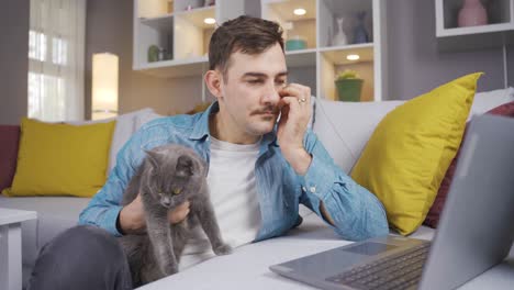 the man works at the laptop and loves his cat.