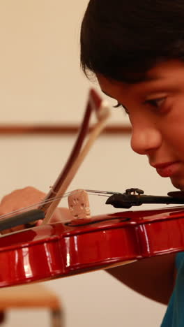 cute pupil playing violin in classroom