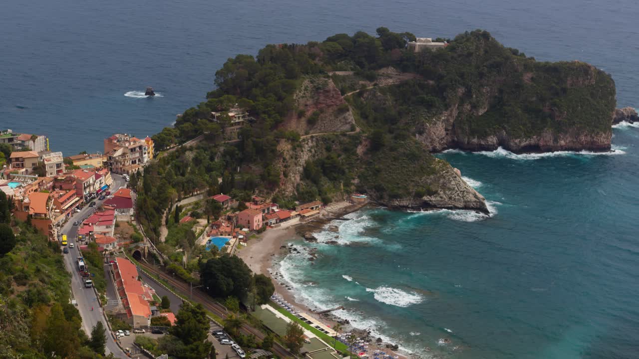 Wide shot of Taormina beach, oceanfront streets, and homes by the sea in Sicily, Italy (Italia)
