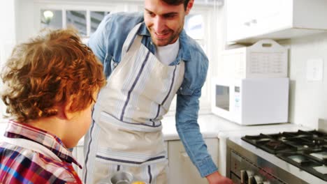 Father-and-son-removing-cupcakes-tray-from-oven