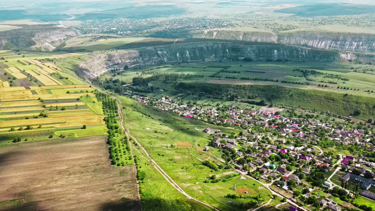 Aerial drone view of nature, valley with river and village, hills and fields, greenery, Moldova