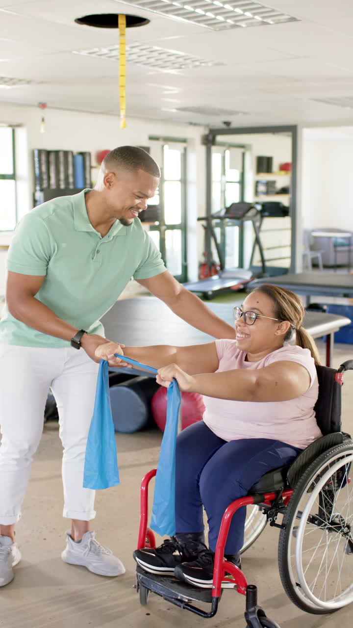 Vertical video: Physical therapist assisting woman in wheelchair with resistance band exercises