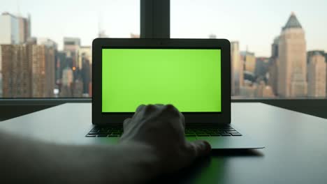 computadora con pantalla verde en un edificio de oficinas moderno con fondo de paisaje urbano.