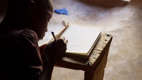 black african children kid study alone writing on notebook preparing homework for school in remote village of africa