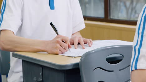 Educación-Académica,-Aprendizaje-Y-Estudiante-Escribiendo-Un-Examen,-Prueba-O-Evaluación-En-La-Mesa,-Mano-Con-Bolígrafo-En-Una-Clase-En-La-Escuela