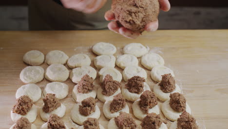 el panadero pone el relleno de carne picada en los trozos de masa. cocinar dumplings