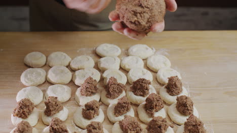 the baker puts the minced meat filling into the dough pieces. cooking dumplings