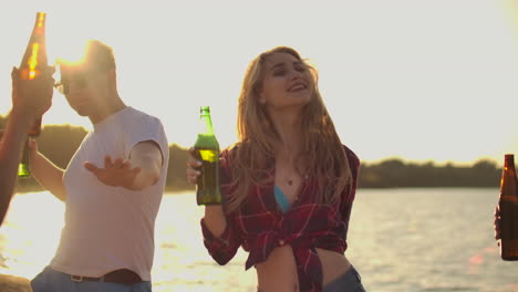 chicos y chicas están moviendo sus cuerpos jóvenes en danza con cerveza en la fiesta de playa de verano caliente. los jóvenes están disfrutando de la fiesta al aire libre de verano.