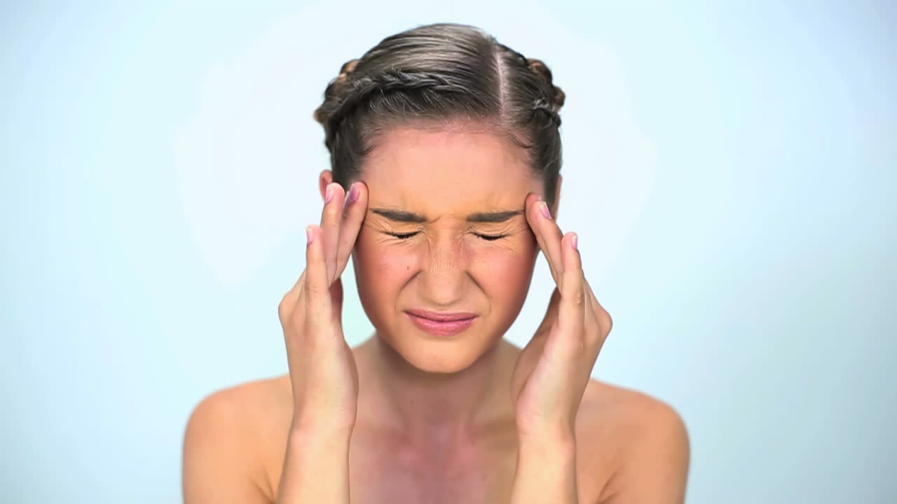 Unsmiling young woman put her hands on temples