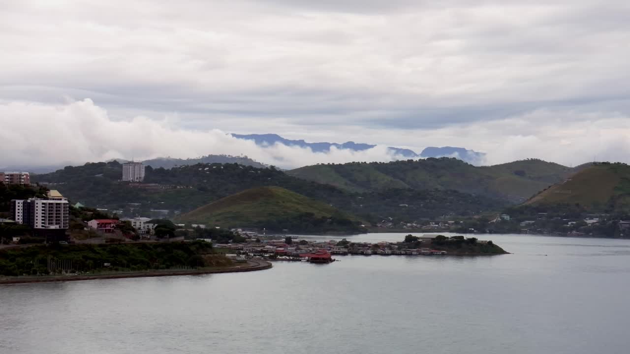 Coastal City with Mountains and Cloudy Sky