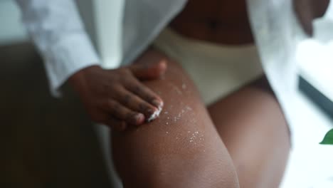mujer aplicando exfoliante corporal a su pierna