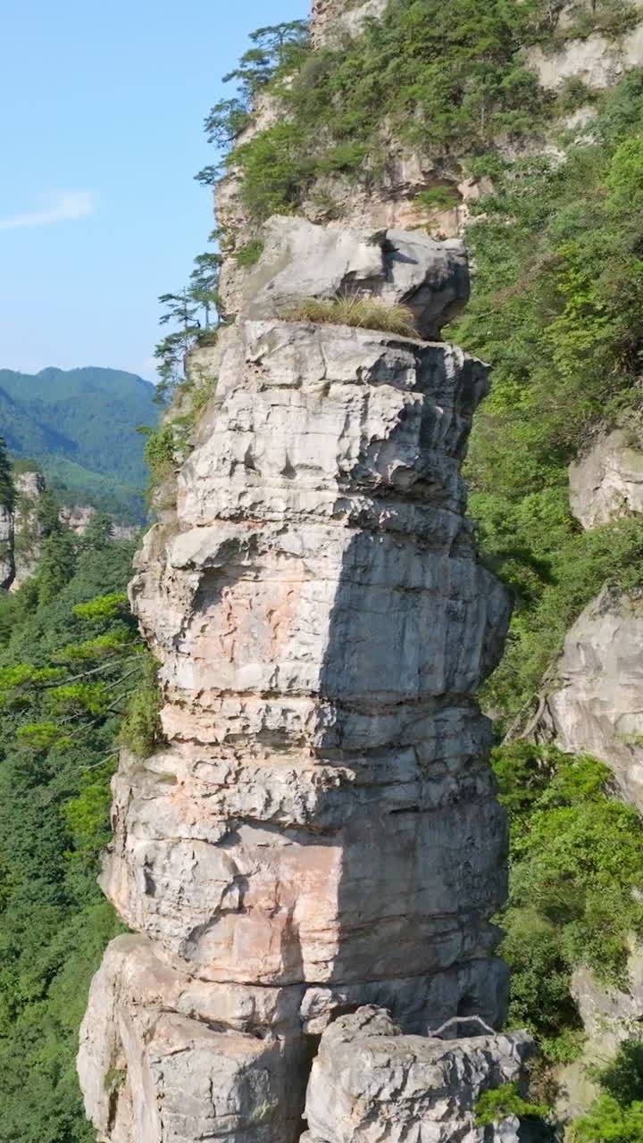 Vertical aerial circling a rocky cliff in Huangshizhai, Zhangjiajie park, China