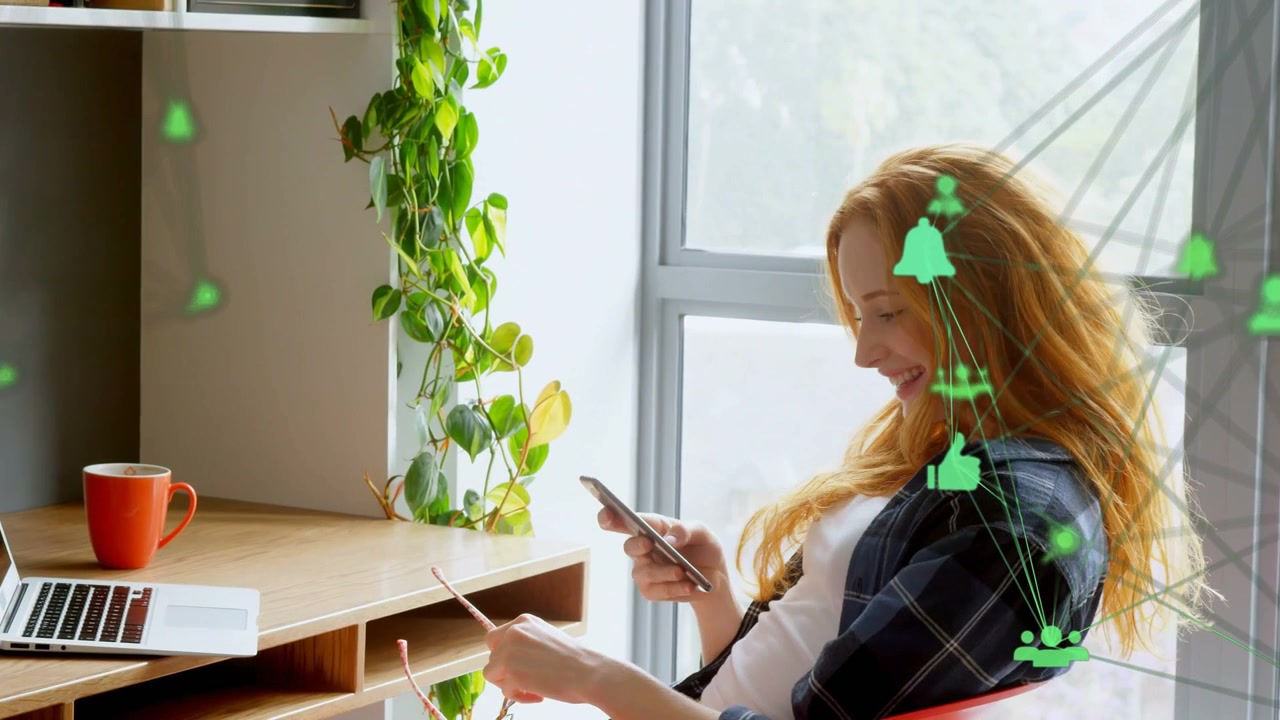 Donna adulta che digita su una scrivania tecnologica di casa, icone verdi che compaiono, dando un'occhiata, toccando il telefono e riprendendo il lavoro.
