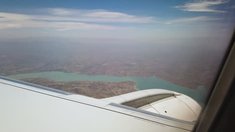 subjective view of a passenger in an airplane flying over a large lake with turquoise water