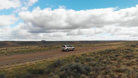 Aerial-orbit-around-car-on-dirt-road-at-Pilot-Butte-Wild-Horse-Scenic-Loop,-Wyoming-USA