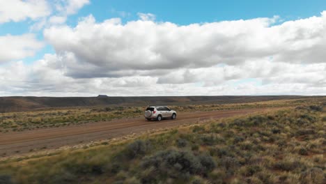 órbita aérea alrededor del coche en el camino de tierra en pilot butte wild horse panorámico bucle, wyoming ee.uu.