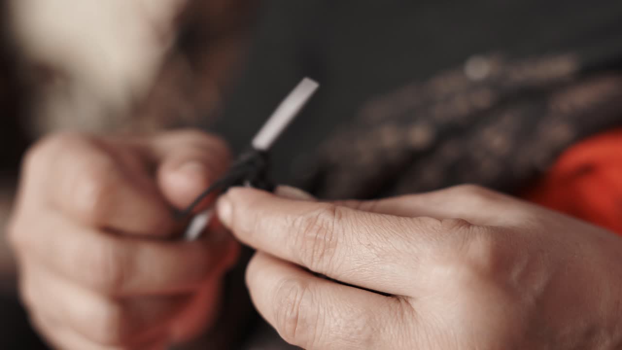 Close up of woman's hands knitting with black wool and needle crafts
