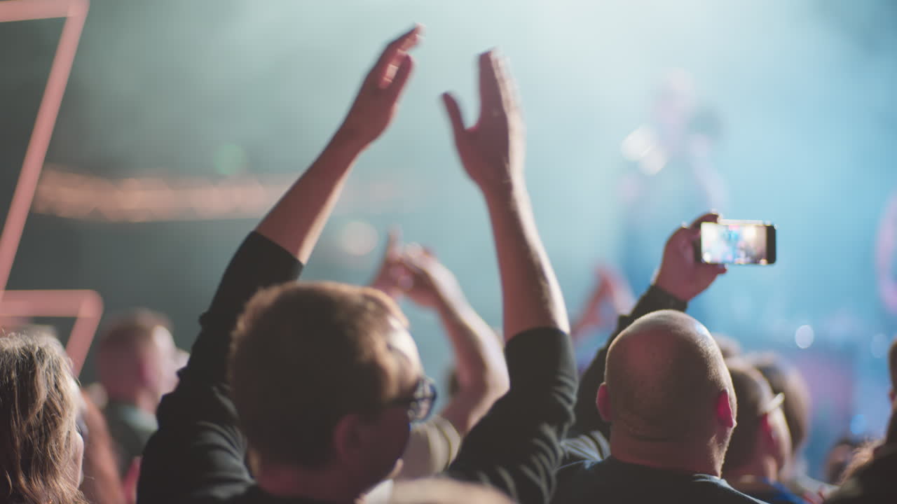 Publikum klapper og optager til en livekoncert med scenelys