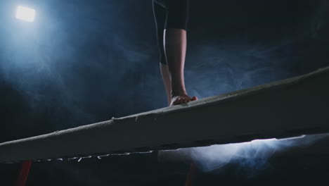 legs professional girl gymnasts jump in slow motion in the smoke on the balance beam. women's artistic gymnastics