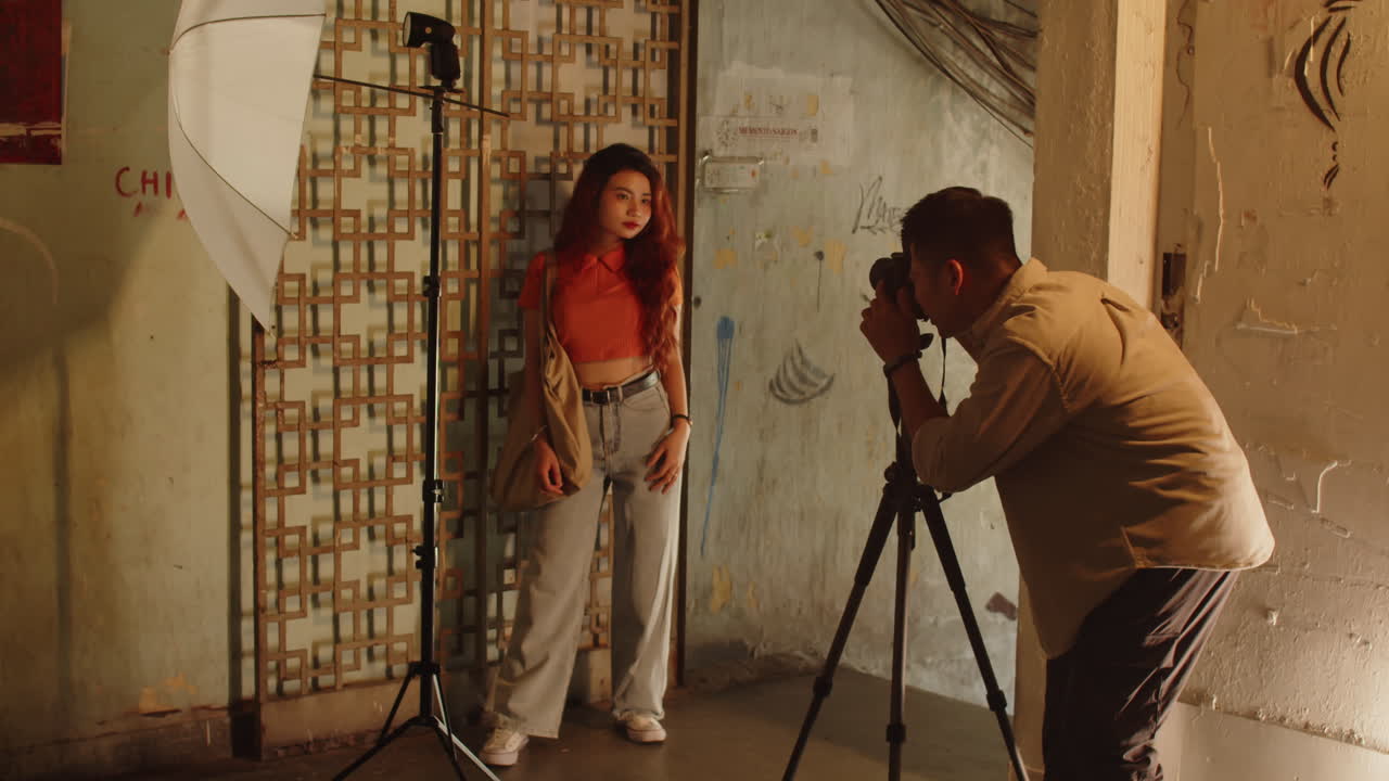 Male Photographer Taking Pictures of Model Posing on Decorated Wall