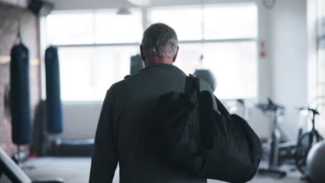man walking in a gym with a gym bag