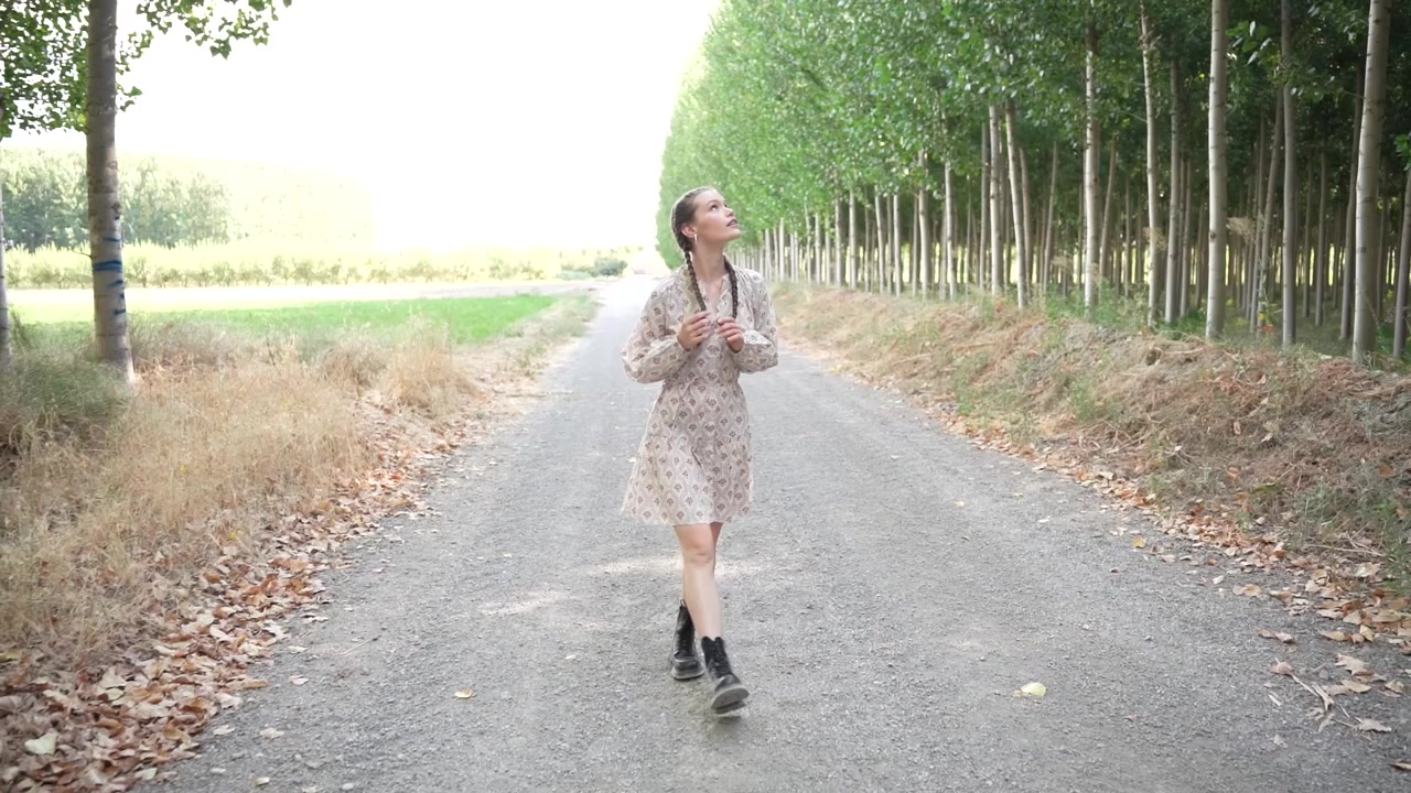 自然に囲まれた穏やかで美しい田舎道で、楽しそうに踊る少女。