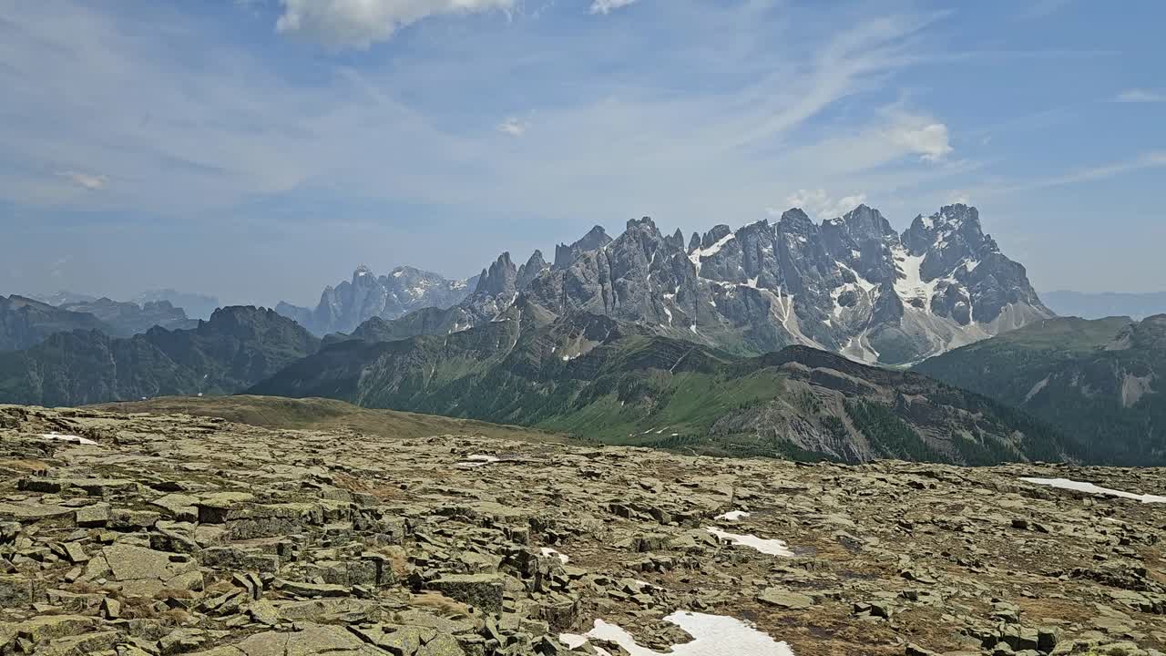 Panorama der Pale di San Martino von der Cima Juribrutto aus, mit einigen roten Felsen im Vordergrund.