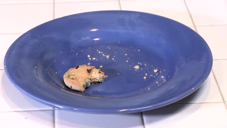 a half eaten cookie on an empty plate with crumbs