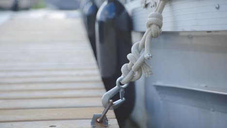 cuerda de barco flotante unida al gancho de acero rígido en un muelle de madera