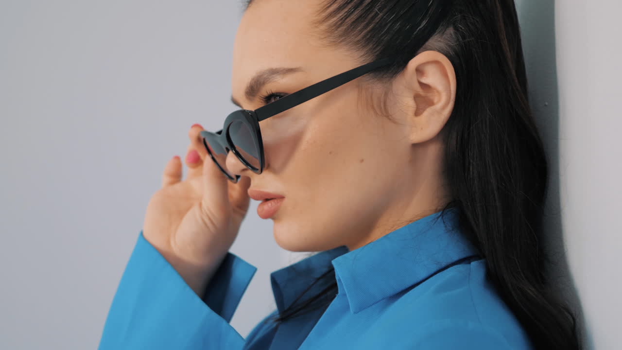 파란 셔츠와 선글라스를 입은 세련된 여성