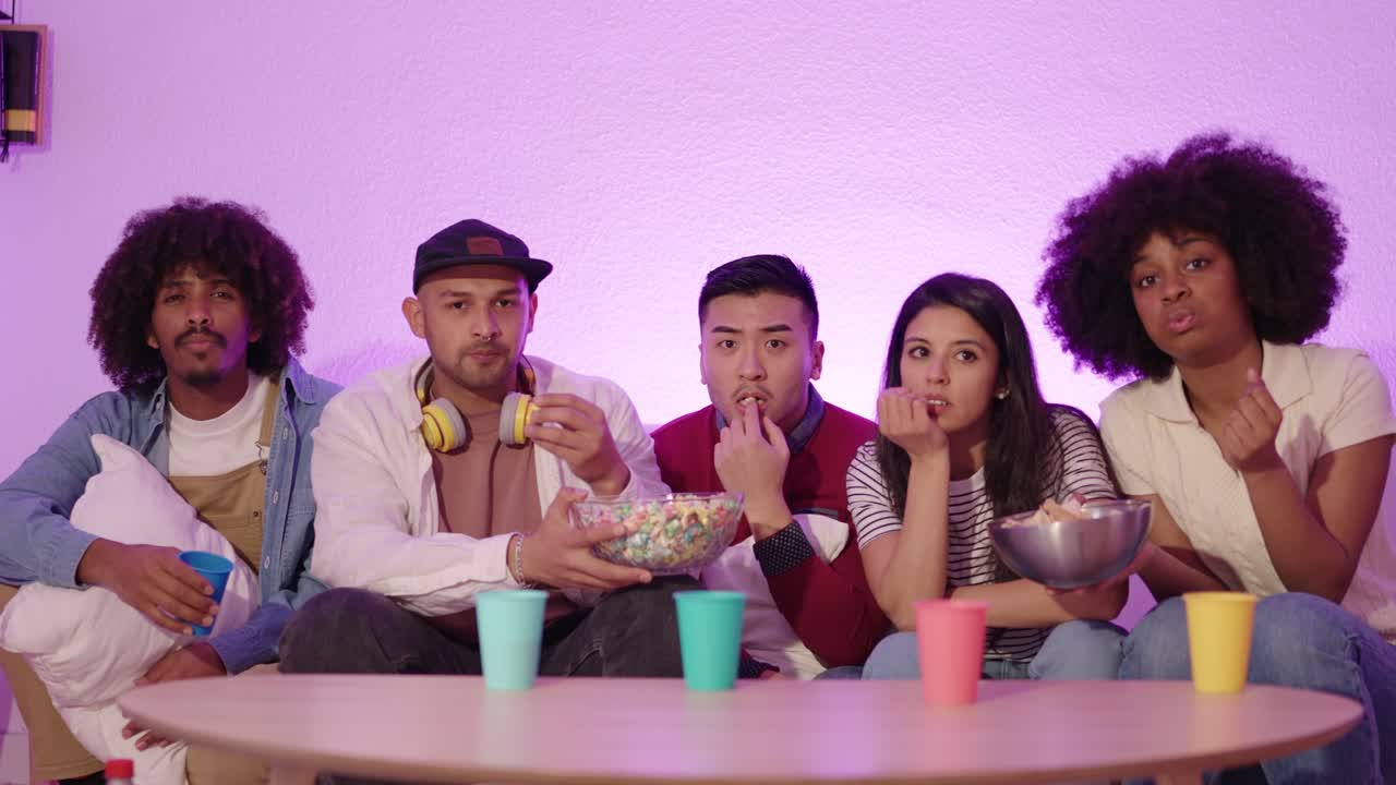 A group of friends watching TV and eating snacks