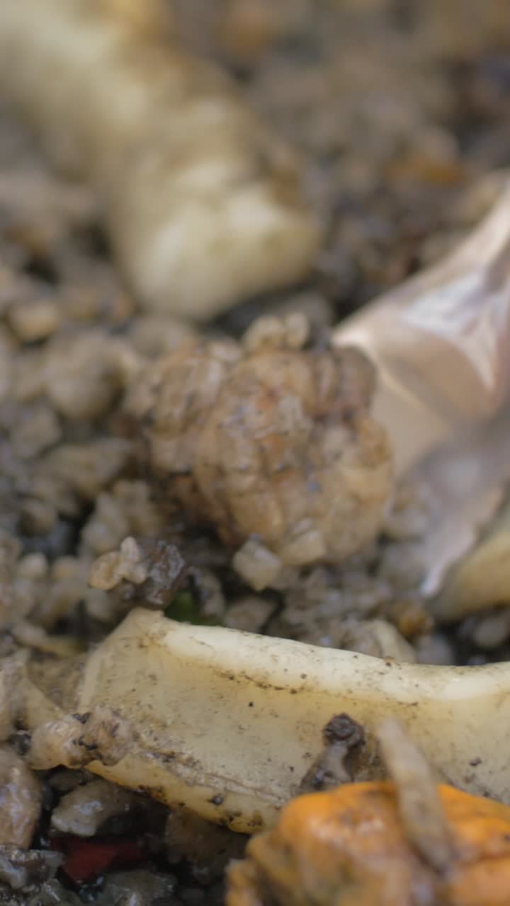 Mescolando una deliziosa paella di mare con nero di seppia e cozze