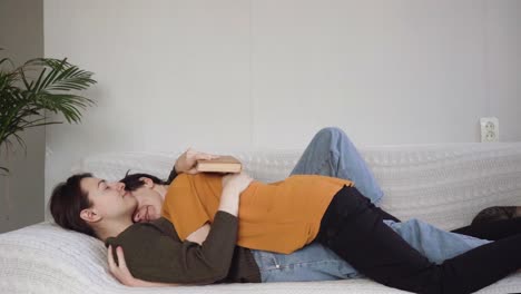 two girls are lying on the couch and hugging