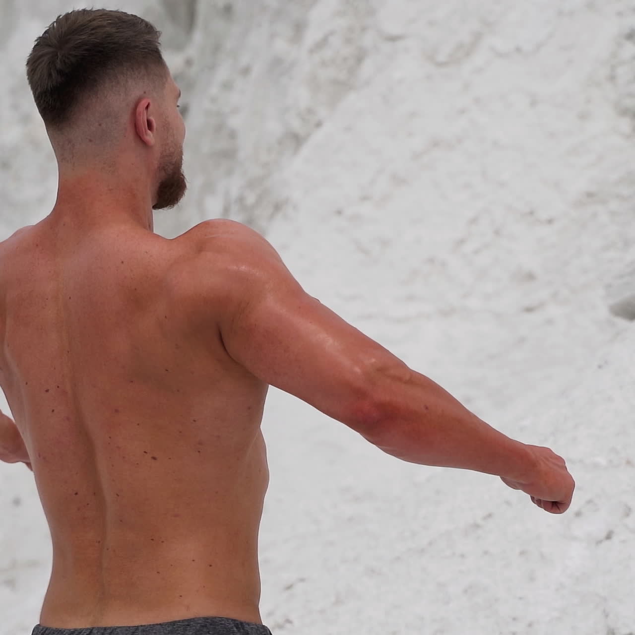 Muscular shirtless man showing his body on the natural background of mountains. Strong bearded man in the open air.