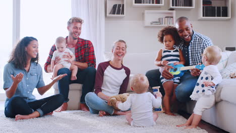 friends with toddlers playing and singing on floor and sofa