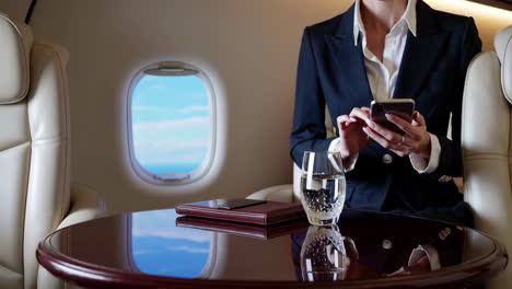 businesswoman using smartphone on a private jet
