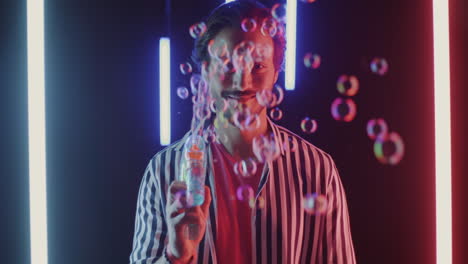 man blowing bubbles in neon lights